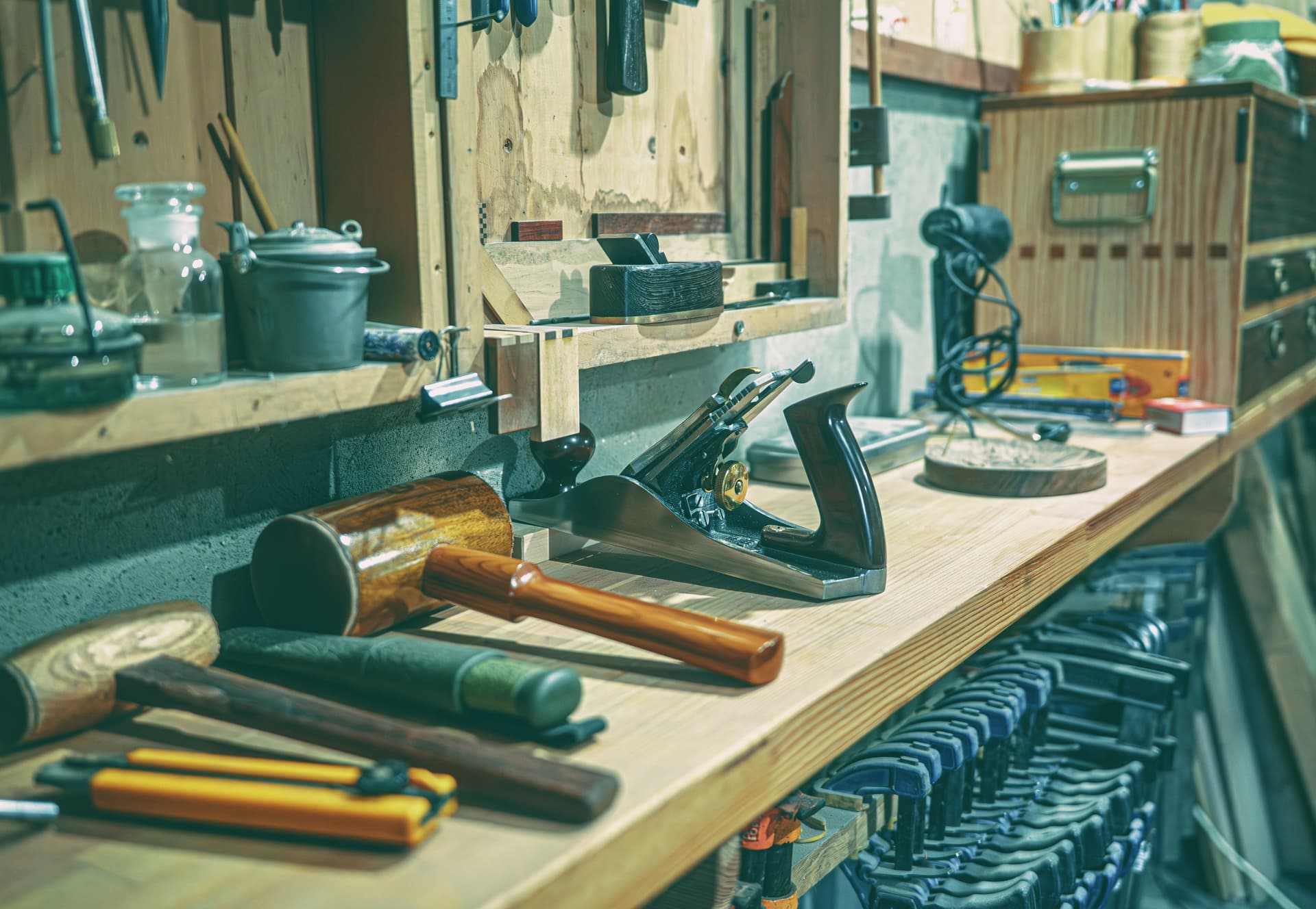 A workshop bench with woodworking tools and clamps arranged on it